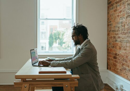 une personne assise à un bureau avec un ordinateur portable devant un mur de briques