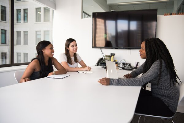 Trois personnes assises autour d'une table et en cours de dialogue